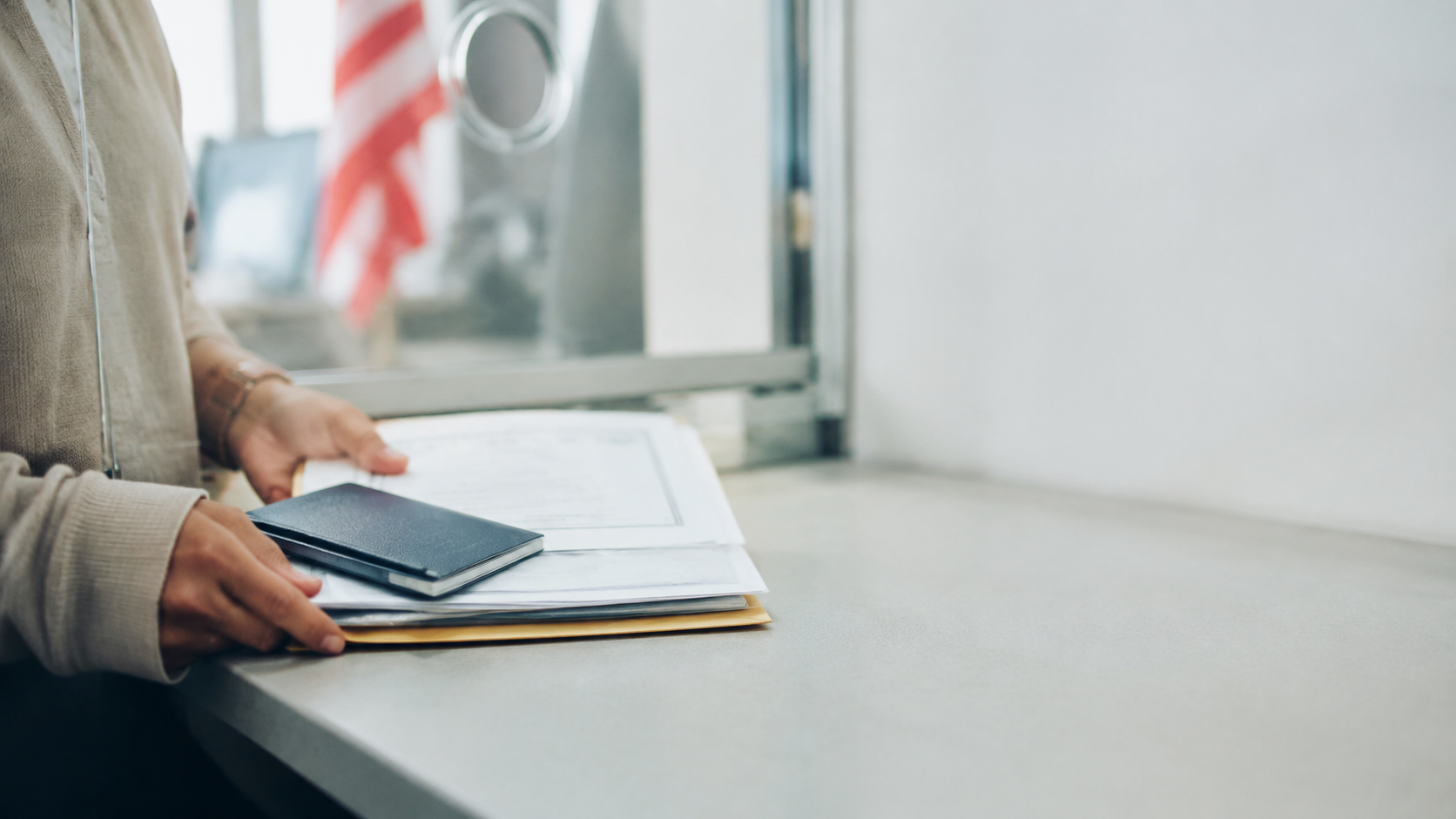 Applicant holding a passport and immigrant-visa documents beside a generic court order at a consular review desk